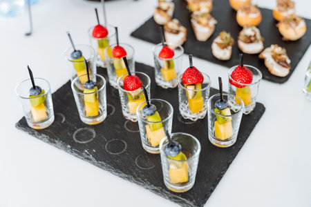 Appetizer cupcakes in a glass, serving food in glassware, skewers with berries and cheese, stone black serving board. High quality photoの写真素材