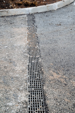 Drainage system on the road, asphalt road, ditch with rainwater collection grate, storm drain, rain collection system on the road. High quality photoの写真素材