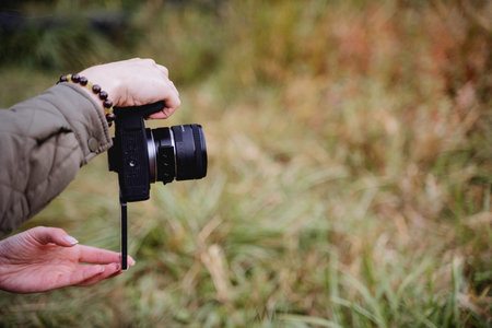 Digital camera in photographer's hands, hands holding camera, vertical shooting, flip-up camera screen, mirrorless camera. High quality photoの写真素材