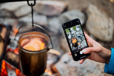 Taking pictures on the phone of a pot on the fire, a female hand with a smartphone filming the food cooking process, art photography, food photo. High quality photoの写真素材
