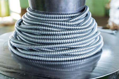 Metal hose wound on bobbin, insulation for wire, cord braid, steel product, metal corrugation. High quality photoの写真素材
