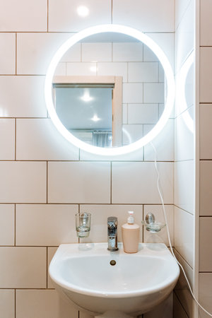 Interior of a modern bathroom with white tiles and a round mirrorの写真素材