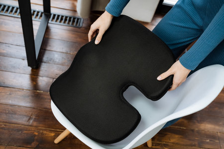 Black orthopedic pillow for correct posture while sitting on a chair at a table, corrective chair...