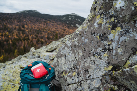 Small format first aid kit on the backpack, safety concept in the mountains, trekking on the rocks,...