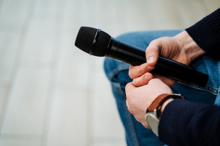 Black microphone in speaker's hands, man holding stage microphone in hand, speaker at speech, business conference concept. High quality photoの写真素材