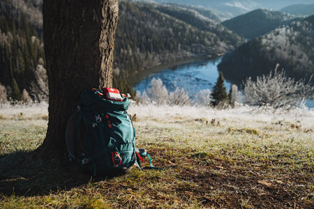 Beautiful mountain landscape, backpack standing by a tree, first aid kit lying on backpack, outdoor recreation, camping in the forest. High quality photoの写真素材