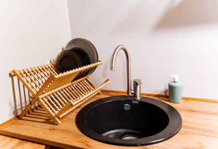 Black sink sink, kitchen utensils, wooden plate dryer, artificial stone sink. High quality photoの写真素材