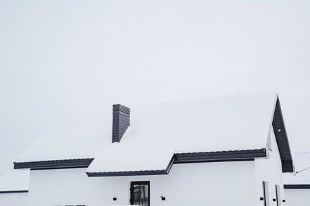 Country house, winter landscape, roof of the house covered with snow, chimney pipe sticking out of the snow, glass door. High quality photoの写真素材
