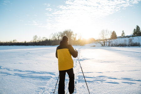 Rear view of man on skis, man in yellow jacket skiing in the snow. High quality photoの写真素材
