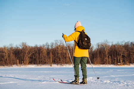 Woman on skis rolling on snow on the background of the forest, winter walk in the fresh air, training in the park. High quality photoの写真素材