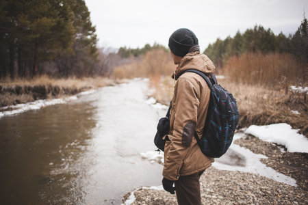 A man at a scenic river with his backpack.