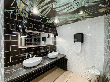 This building property features a bathroom with dual sinks, a wall-mounted mirror, and a composite...