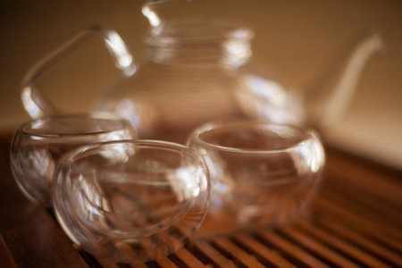 A glass teapot and cups are displayed on a wooden table, showing elegant drinkware and servewareの写真素材