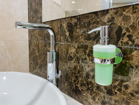 A plumbing fixture containing a bathroom sink attached to the wall, with a soap dispenser for dispensing fluid located nearby.の写真素材