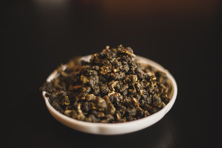 A bowl of green tea leaves, a superfood rich in antioxidants and nutrients, sitting on a table, ready to be used as an ingredient in a recipe or dishの写真素材