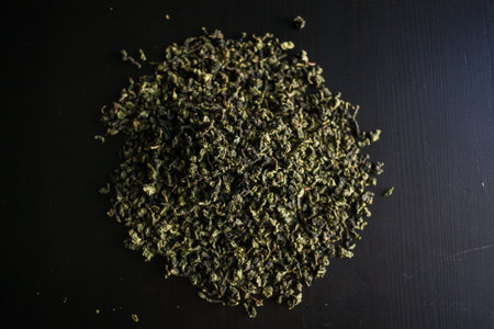 A pile of hairlike green tea leaves intricately arranged on a dark surface resembles a plant with branches reaching towards the sky in a captivating macro photography artworkの写真素材