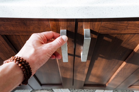 As the person opened the cabinet door with their hand, you could see the hardwood flooring and wood...
