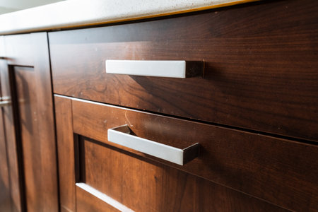 A detailed closeup of a hardwood cabinetry piece with a white handle, showing the wood grain and varnish finish. This chest of drawers is a beautiful addition to any propertyの写真素材