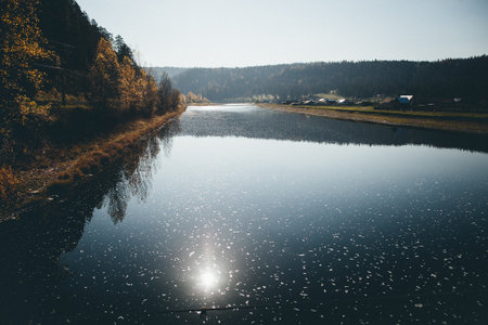 The calm water of the lake mirrors the sun, creating a beautiful reflection of the sky and clouds in the natural landscape of the lacustrine plainの写真素材