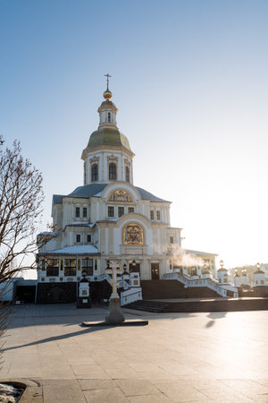 A stunning white and gold church with a cross in front, set against a backdrop of a clear blue sky. This historic site is a place of worship and a monumental building in the cityの写真素材