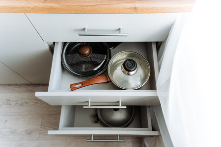 A kitchen drawer filled with pots and pans, essential home appliances made of metal and used for cooking on gas or wood stovesの写真素材