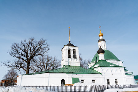 A white building with a green roof and a bell tower against the clear blue sky. The fixture stands...