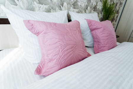 A cozy bed with purple linens and magenta pillows, adorned with pink petals. The comfort of the...