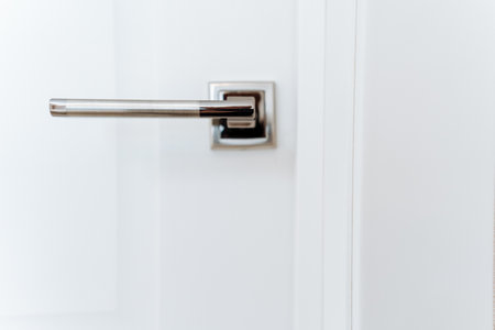 Shiny chrome hardware, metal handle on white door, frontal view of door handle. High quality photoの写真素材