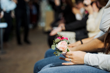 At the formal event, a woman stands holding a beautifully arranged bouquet of flowers in her hand, a happy smile on her face as petals cascade down her thighの写真素材