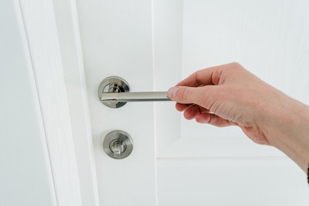 Hand holding door handle on white background, man opening snow-white door to room. High quality photoの写真素材
