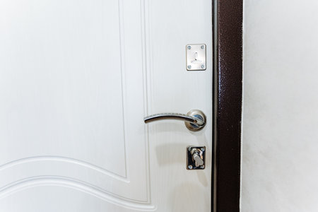 A closeup of a white door with a metal handle, a household hardware fixture. The door is made of wood or composite material, a common feature in home doorsの写真素材