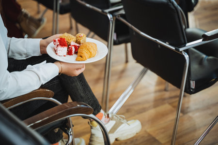 A person is seated in a wooden chair, holding a plate of delicious food. The cuisine looks mouthwatering and the tableware is elegant. It seems like a delightful dish ready to be enjoyedの写真素材
