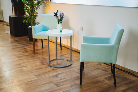 Two chairs are positioned near a table adorned with a vase of flowers. The furniture is made of...