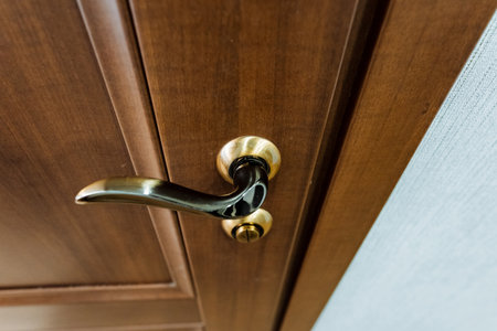 A detailed closeup of a wooden door handle showing a beautiful wood stain pattern on the hardwood fixture. A classic household hardware pieceの写真素材