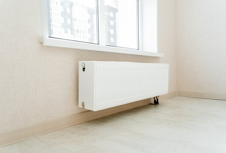 The white heating radiator in the apartment is under the window, the heating system is in the house. High quality photoの写真素材