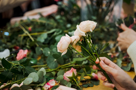 The person is holding a beautiful bouquet of flowers, showing a variety of blooms from the rose...