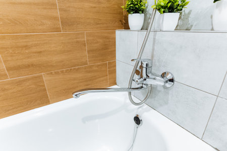 A plumbing fixture combining a bathtub and shower head is installed in the bathroom of a house. The...