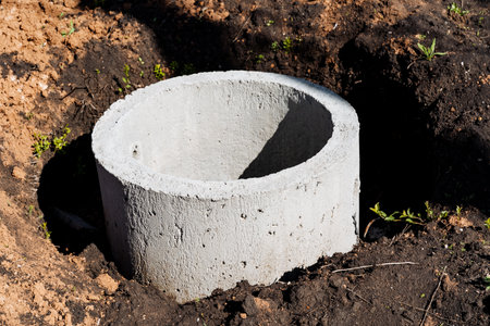 A concrete drainage pipe is ready for installation in freshly dug earth on a construction site. This infrastructure project is essential for water management and sanitationの写真素材