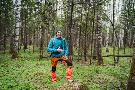 A man with a smile is standing on a rock surrounded by trees and grass in the middle of a natural...