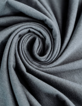A macro photography of a swirl of gray fabric resembling a water pattern, with hints of electric blue. The monochrome image has a petallike appearanceの写真素材