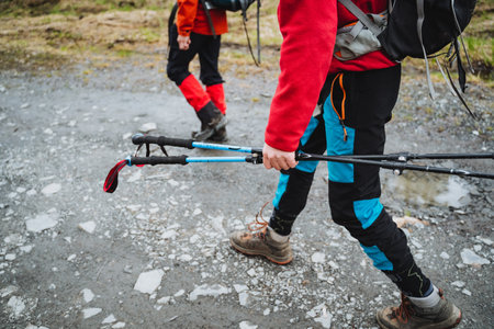 Closeup of two hikers dressed in outdoor gear using trekking poles while walking on a rocky trail. They are enjoying a nature adventure and exploring the outdoorsの写真素材