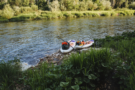 At the rivers edge, two inflatable boats lie peacefully amidst lush greenery and calm waters,...