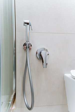 The bathroom features a toilet and a wallmounted shower head, complete with plumbing fixtures for fluid management. It is equipped with essential household equipment for a comfortable experienceの写真素材