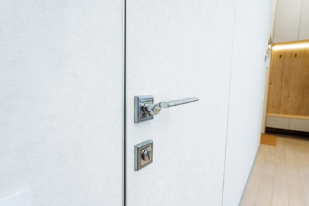 A detailed view of a white door with a modern chrome handle, showing elegant design for cabinetry, wood, fixtures, and more. It offers a sleek and contemporary look for home improvementの写真素材