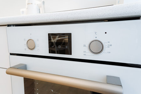 Highlighted by a white oven and modern appliances, the kitchen presents a modern cooking space. The setting offers a detailed view of a chic and practical area, embodying contemporary designの写真素材