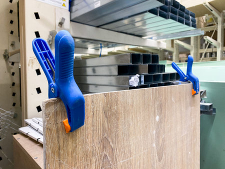 The image shows blue clamps holding a wooden panel in a wellorganized workshop, ideal for DIY projects, cabinetry, and furniture making, highlighting the craft involvedの写真素材