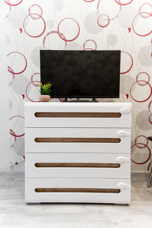 A beautiful white dresser featuring a sleek flat screen television placed on top of it, creating a stylish and modern interior design element that enhances the overall aesthetics of the roomの写真素材