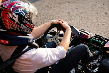 A man in a bright safety helmet expertly drives a colorful gokart on an exhilarating racetrack, demonstrating his skills in this thrilling motorsport enjoyed by enthusiasts worldwideの写真素材