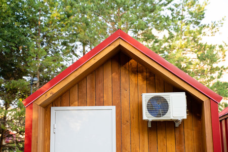 Nestled amidst the trees, there is a small wooden house characterized by its charming red roof and a pristine white door, exuding warmth and inviting comfort within the surrounding natureの写真素材