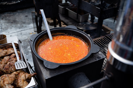 A steaming pot of hearty soup simmers gently on the stove, with a silver spoon inside, ready to...